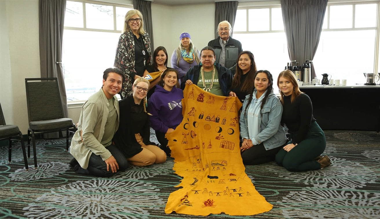 Des membres de notre Indigenous Youth Advisory Council posent avec une peau d’orignal à St. John’s, Terre-Neuve-et-Labrador.