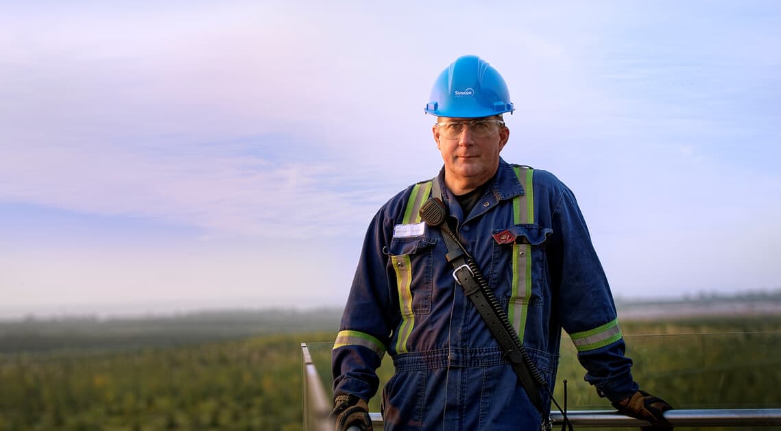 Male worker standing in front of Wapisiw Lookout at Suncor’s Base Plant.