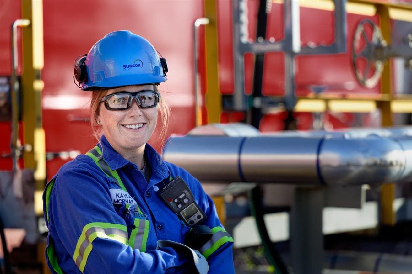 Headshot of a female worker, Kayla McPhail, at the Sarnia Refinery. She is wearing a blue hard hat, safety glasses, high vis jacket and gloves.