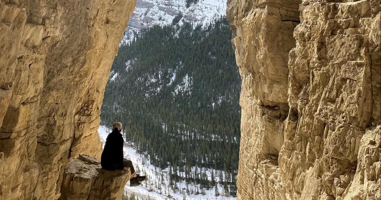 Une femme assise sur des rochers dans les montagnes.