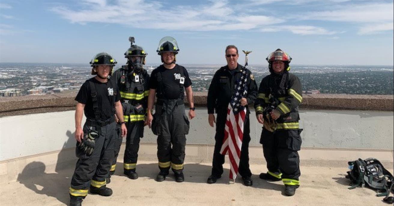 commerce city firefighters in full gear standing on top of building after completing the memorial stair climb