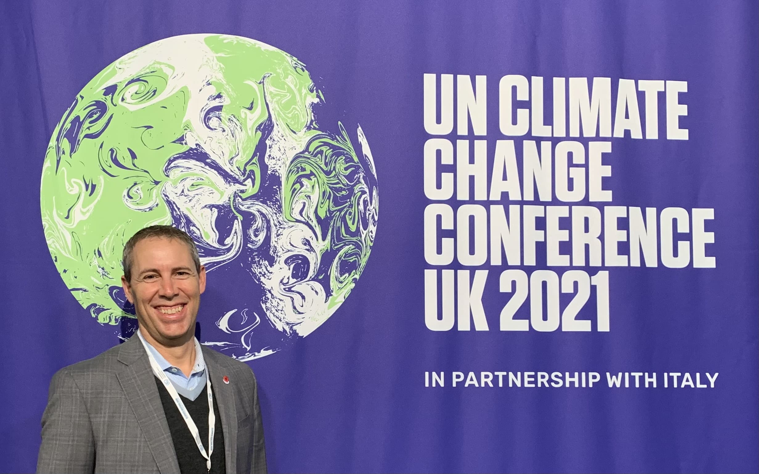 Jon Mitchell, vice-président du développement durable devant la bannière cop26