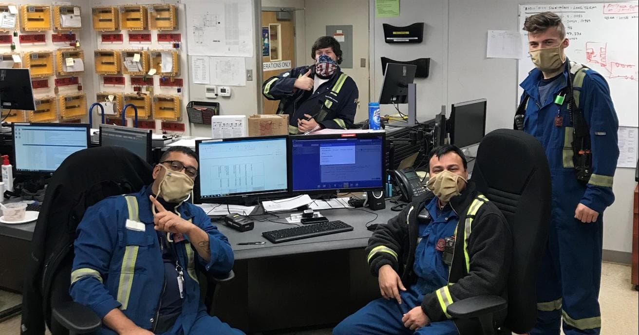workers at east tank farm sitting by their computers wearing personal protective equiptment 