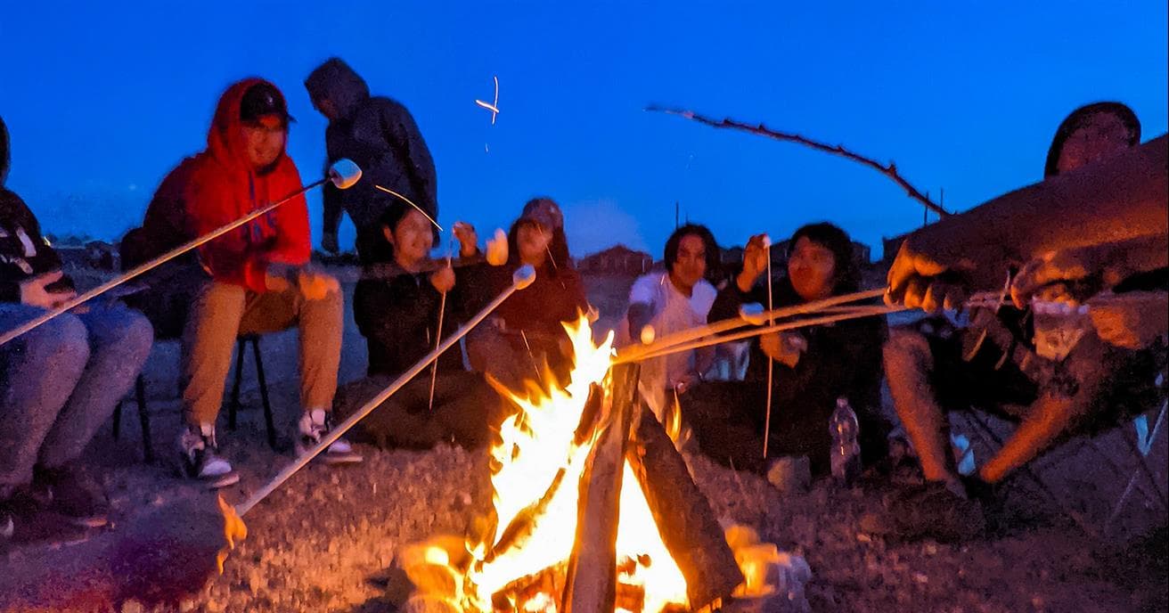 Des étudiants de la communauté crie de Waswanipi rôtissent des guimauves autour d'un feu de camp dans le cadre d'un des programmes de Fusion Jeunesse.