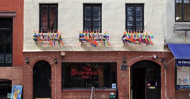 brick building with rainbow pride flags hanging out all of the windows