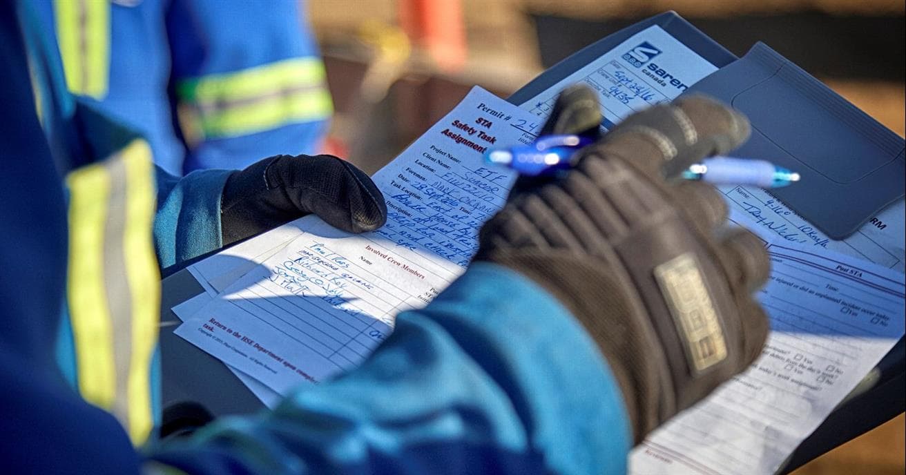 Person in blue personal protective equipment holding paperwork 