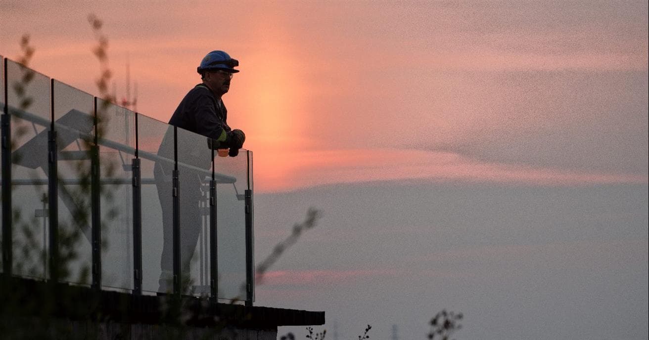 Image du lever du soleil à l'usine de base de Suncor avec l'homme dans l'ombre