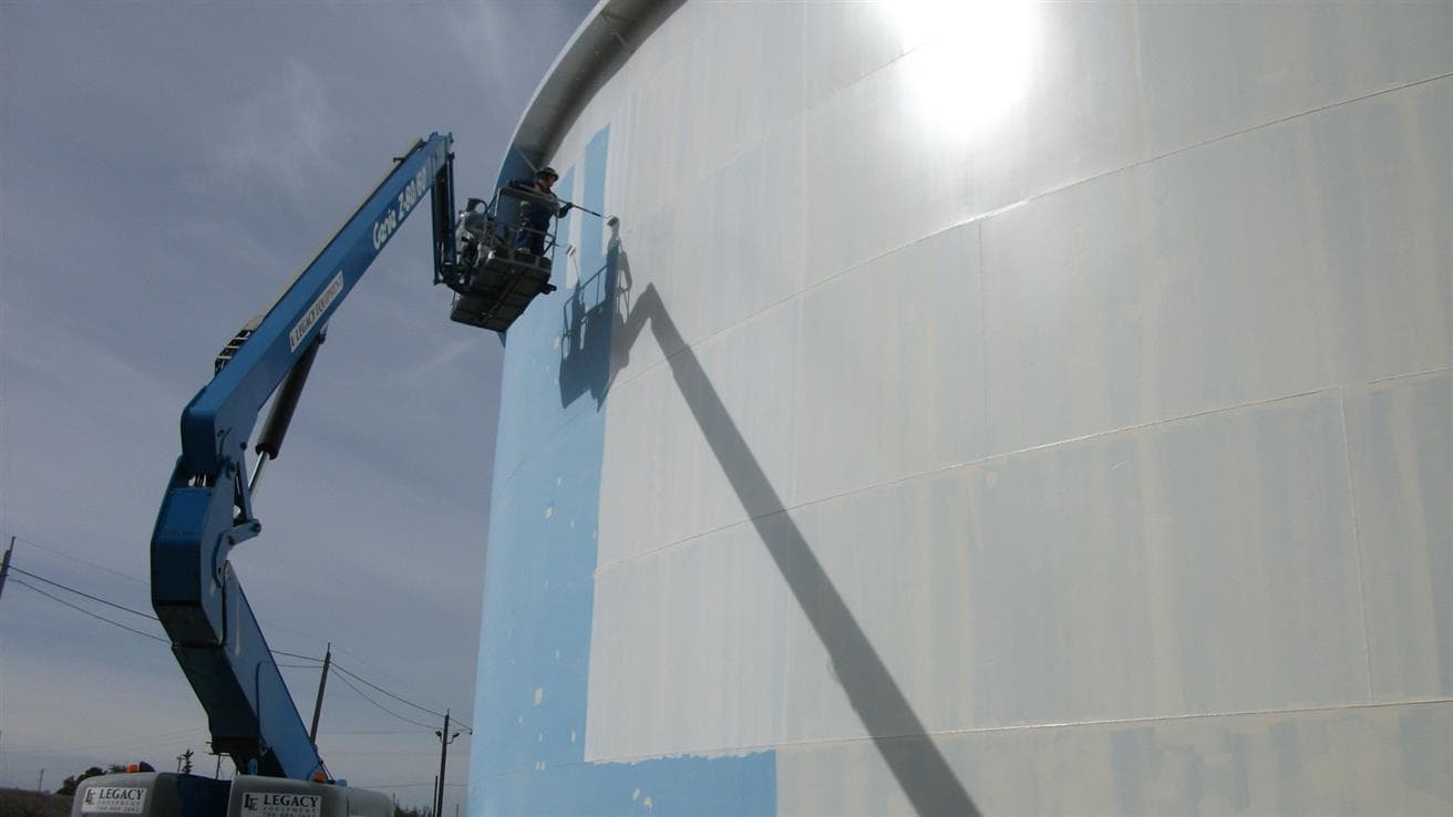 Man painting a white storage tank