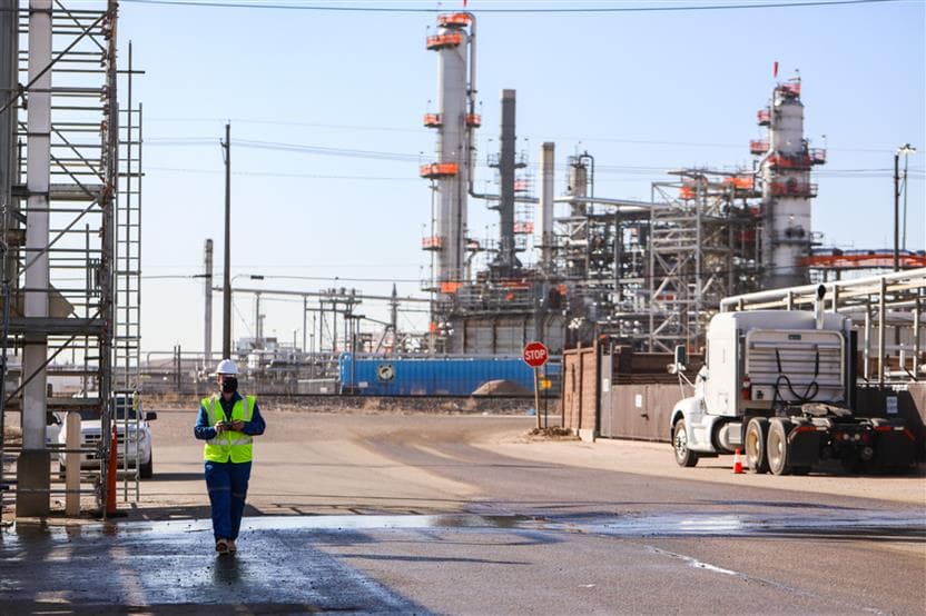 A man in coveralls and a safety vest walking walking around the Commerce City Refinery in Colorado.