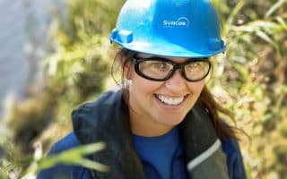 A female worker, Rachel Devereaux, at Wapisiw Lookout. She is wearing a blue hard hat and safety glasses.