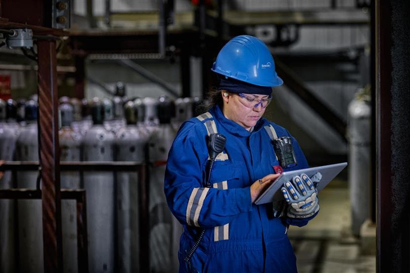 A female worker wearing PPE, using a Microsoft Surface Pro at MacKay River site.