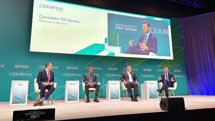 Suncor Chief Financial Officer, Kris Smith participates in a panel discussion at 2023 CERAWeek in Houston, Texas. There are three men sitting on a stage. 